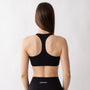 Top sportivo nero da donna indossato con schiena olimpionica: tessuto elasticizzato, supporto confortevole e libertà di movimento per fitness, yoga, pilates e allenamenti.