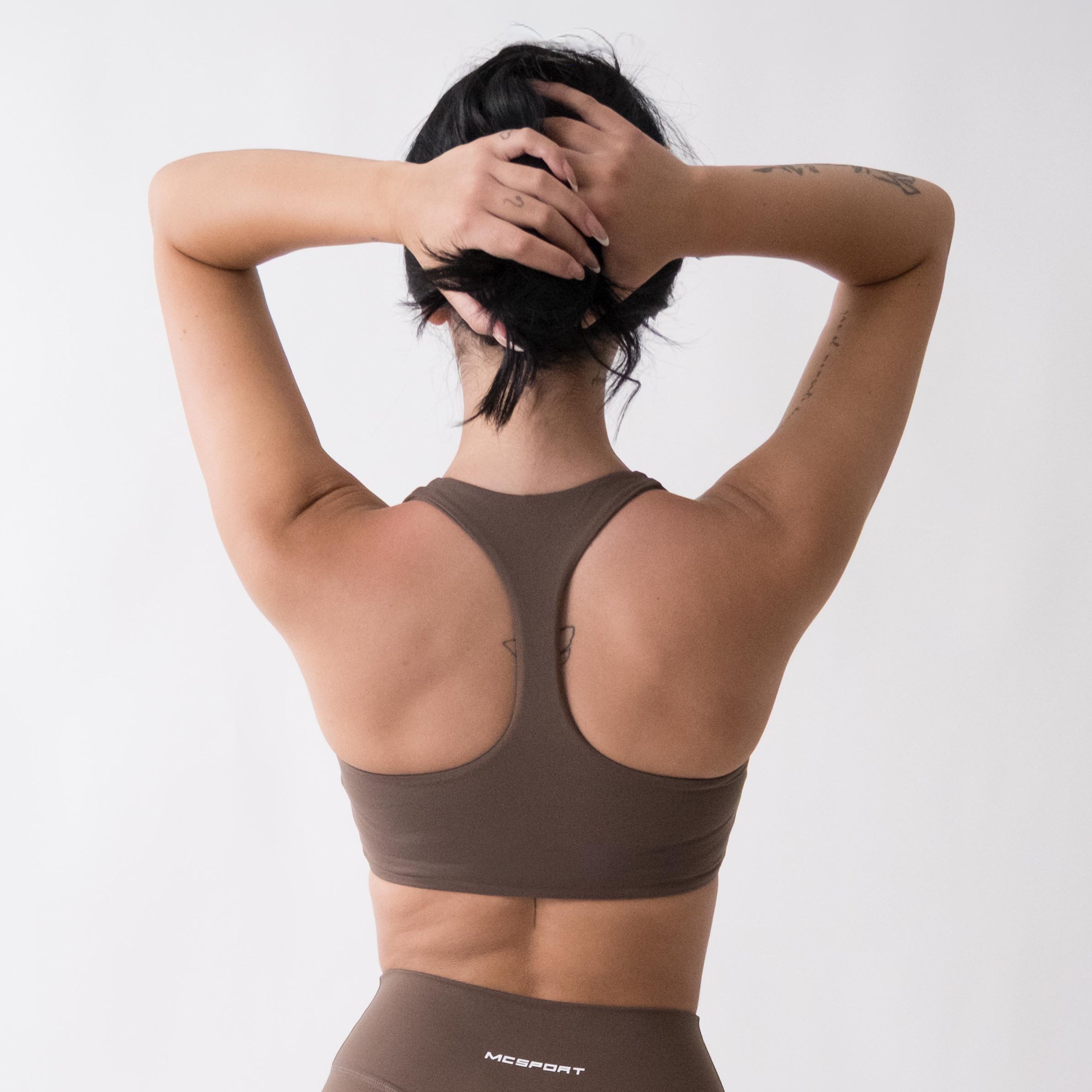 Top sportivo marrone da donna indossato con schiena olimpionica: tessuto elasticizzato, supporto confortevole e libertà di movimento per fitness, yoga, pilates e allenamenti.