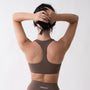 Top sportivo marrone da donna indossato con schiena olimpionica: tessuto elasticizzato, supporto confortevole e libertà di movimento per fitness, yoga, pilates e allenamenti.