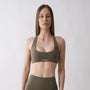 Top sportivo verde da donna indossato con schiena olimpionica: tessuto elasticizzato, supporto confortevole e libertà di movimento per fitness, yoga, pilates e allenamenti.