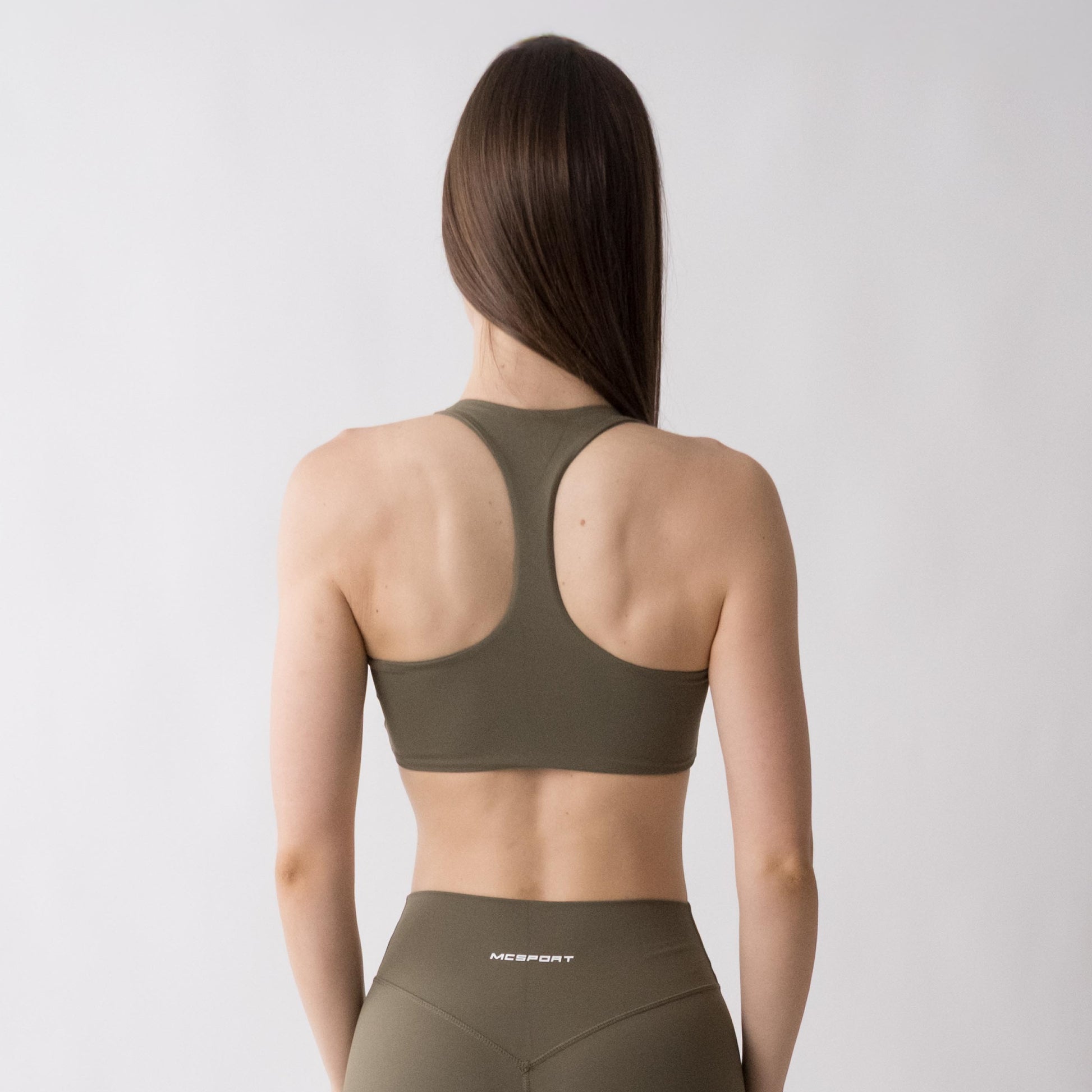Top sportivo verde da donna indossato con schiena olimpionica: tessuto elasticizzato, supporto confortevole e libertà di movimento per fitness, yoga, pilates e allenamenti.