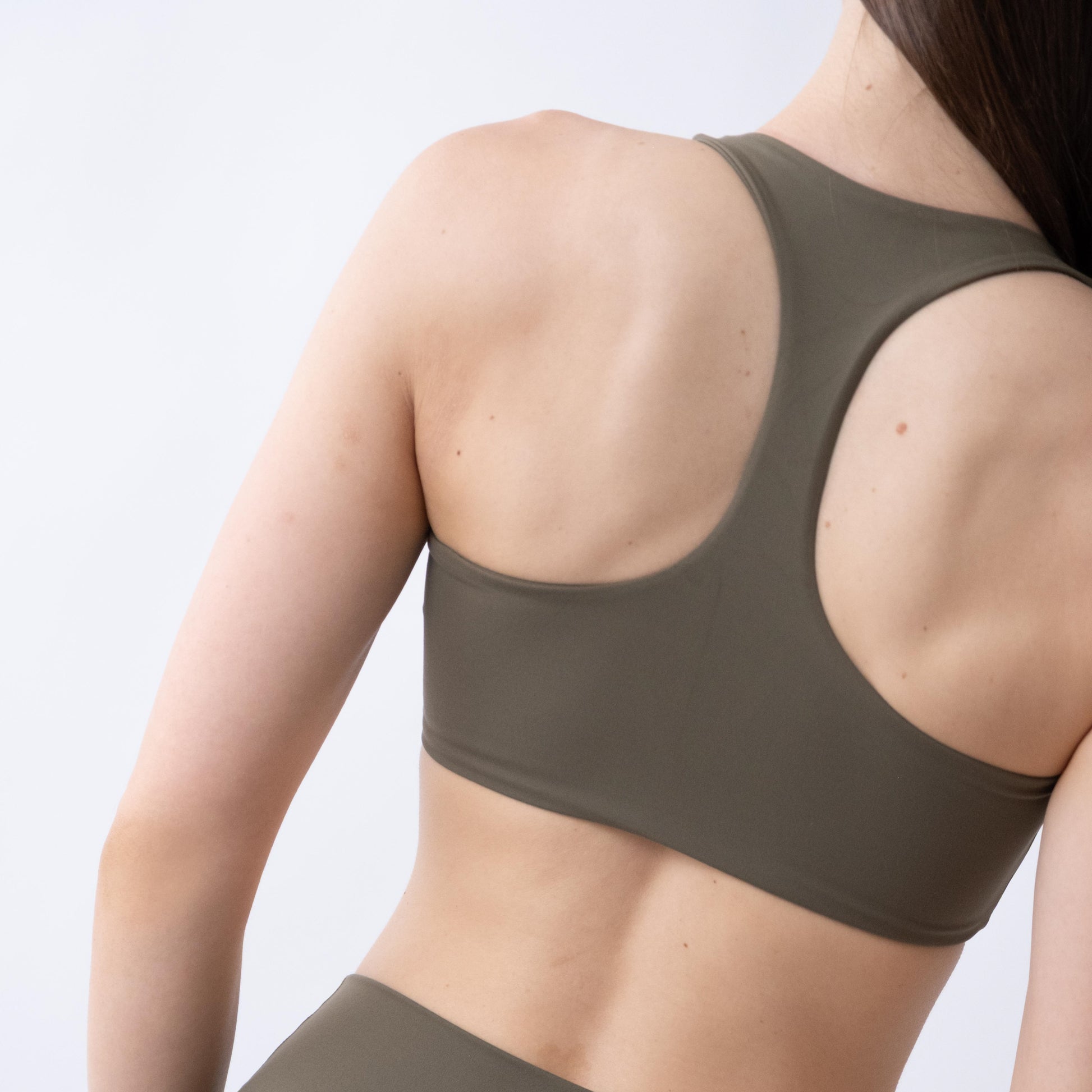Top sportivo verde da donna indossato con schiena olimpionica: tessuto elasticizzato, supporto confortevole e libertà di movimento per fitness, yoga, pilates e allenamenti.