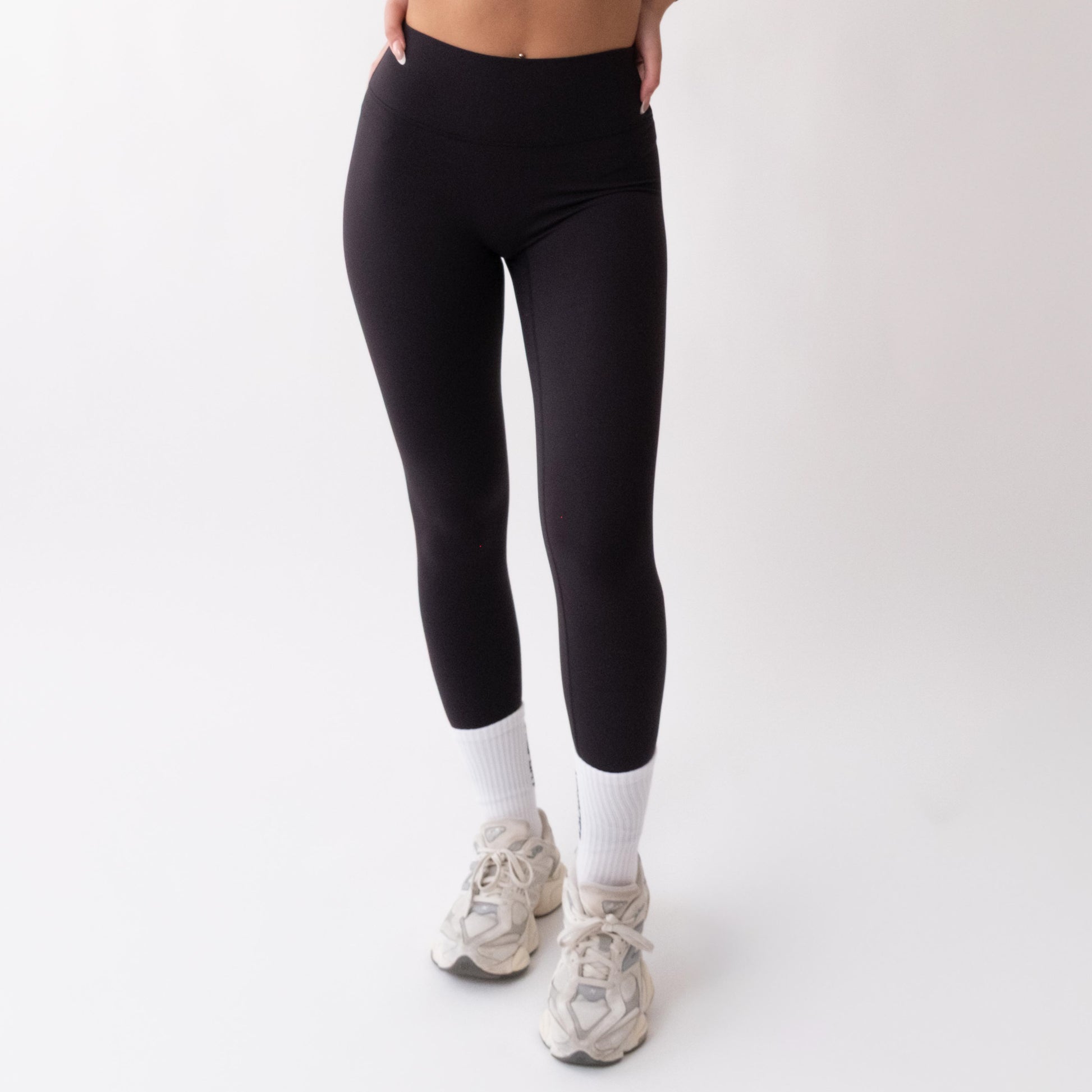 Leggings sportivi neri da donna indossati a vita alta: tessuto elasticizzato, morbido e confortevole per fitness, yoga, pilates e allenamenti di ogni intensità.