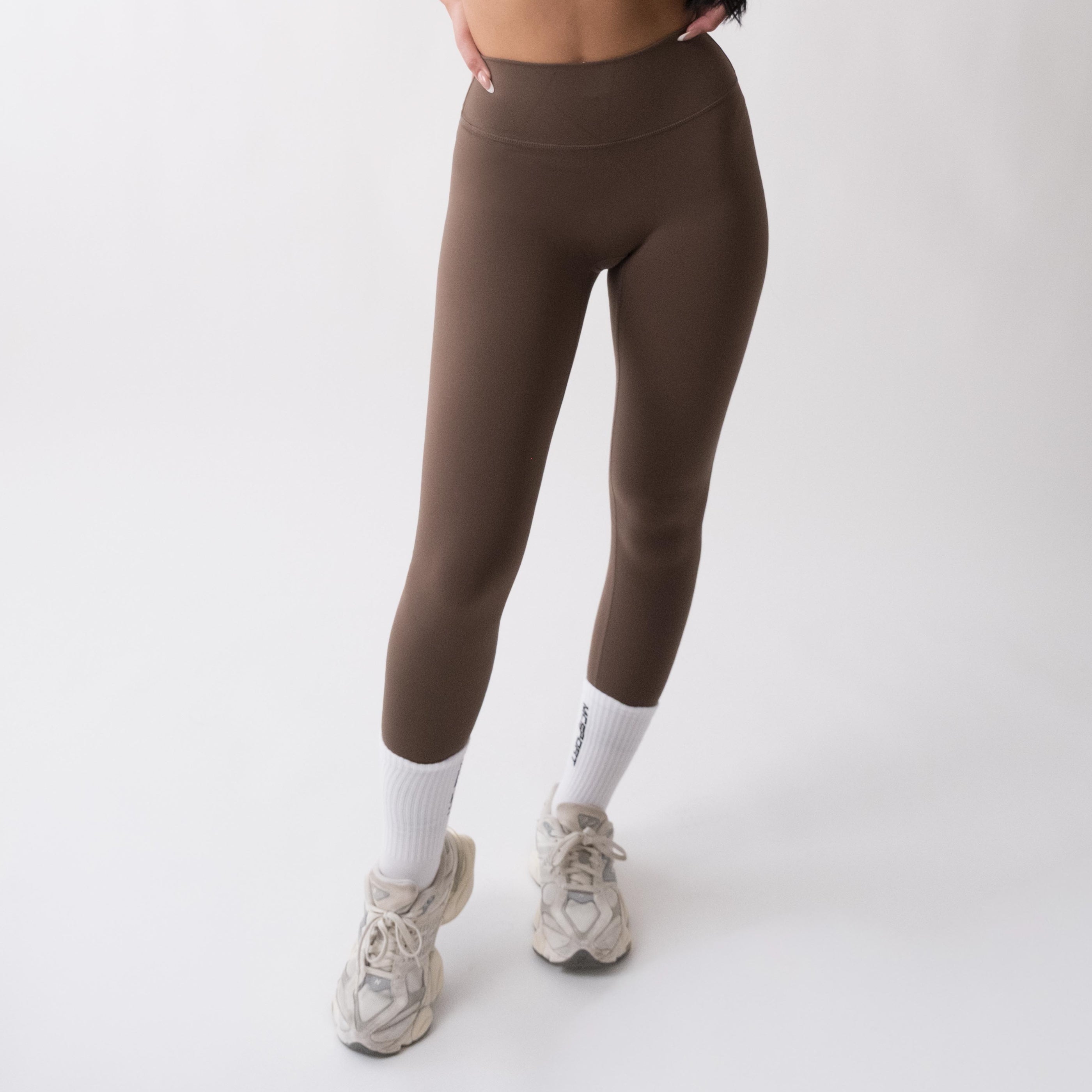 Leggings sportivi marroni da donna indossati a vita alta: tessuto elasticizzato, morbido e confortevole per fitness, yoga, pilates e allenamenti di ogni intensità.