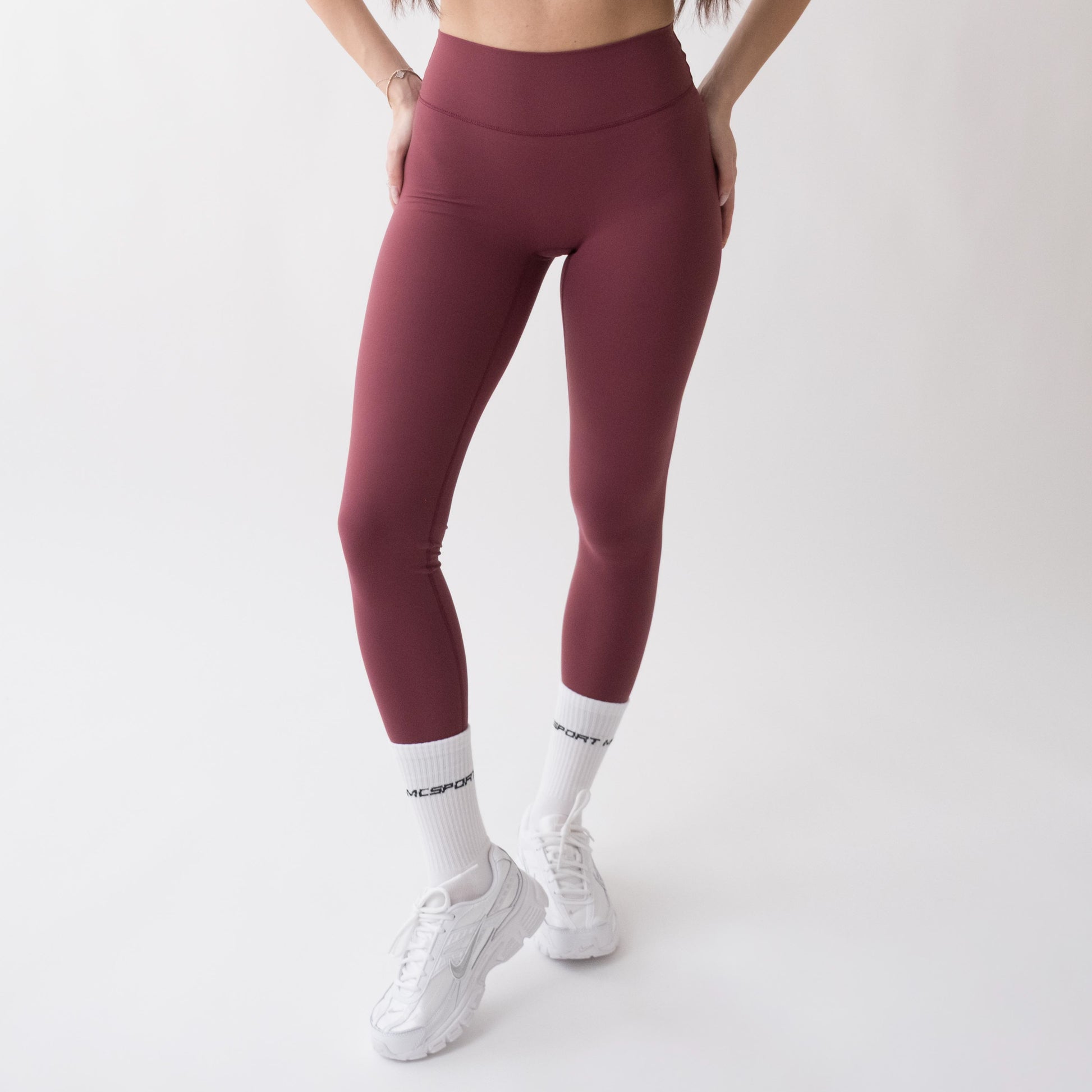 Leggings sportivi rossi da donna indossati a vita alta: tessuto elasticizzato, morbido e confortevole per fitness, yoga, pilates e allenamenti di ogni intensità.