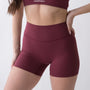 Shorts sportivi rossi da donna indossati a vita alta: tessuto elasticizzato, morbido e confortevole, perfetti per fitness, yoga, pilates e allenamenti di ogni intensità.