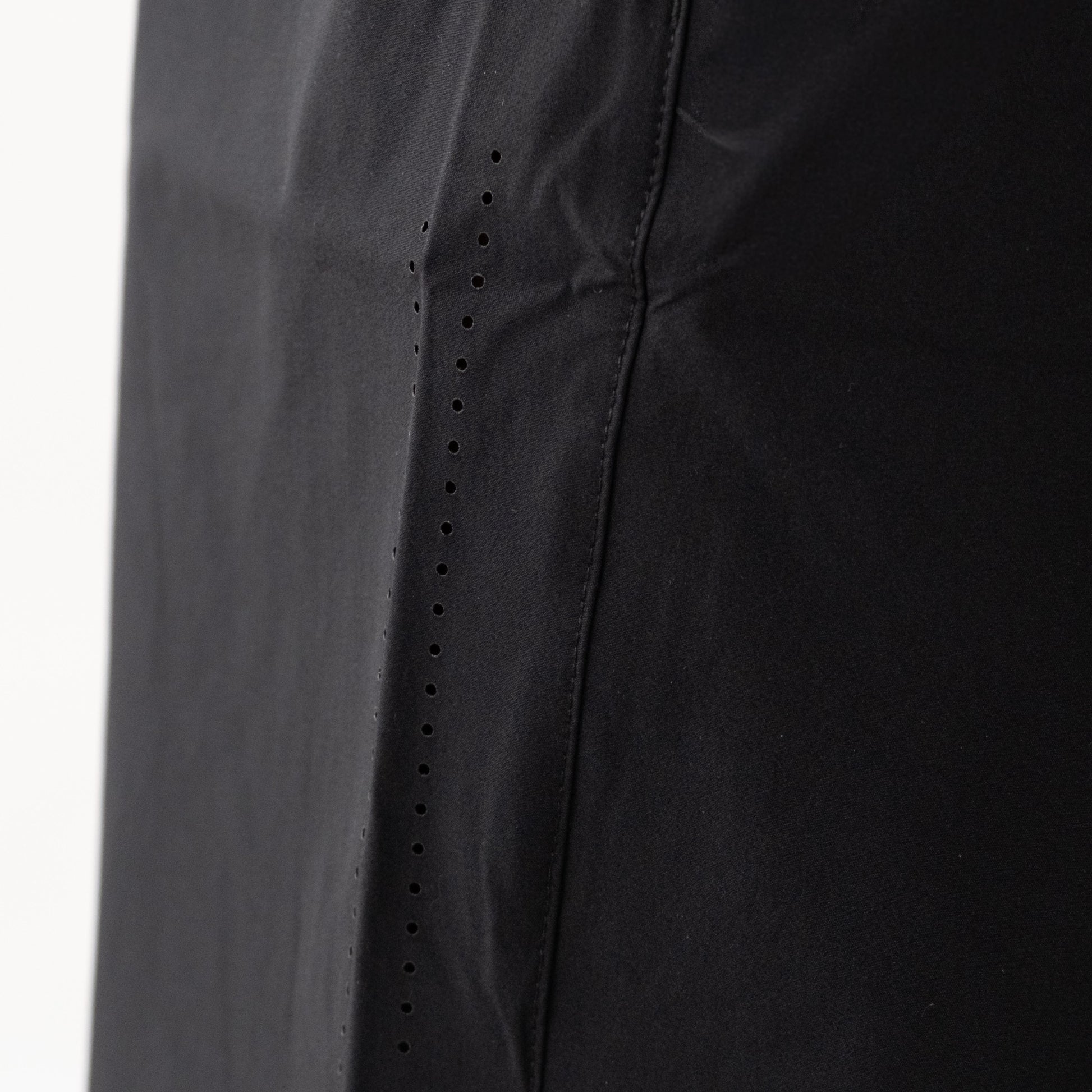 Dettaglio pantaloncini neri sportivi da uomo indossati con ventilazione laser.